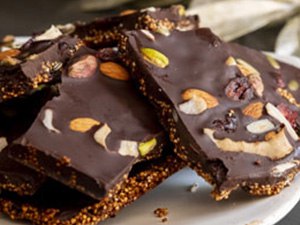 Dark chocolate quinoa bark is stacked on a white plate.