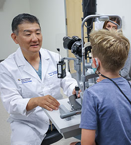 UCI Health pediatric ophthalmologist Dr. Donny Suh examines a young boy's eyes.
