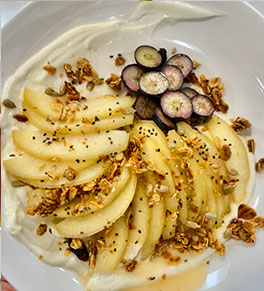 Cinnamon and honey poached pears sit on a bed of Greek yogurt with granola sprinkled over the top.