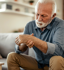 an elderly man sitting on his sofa at home who might be having a heart attack