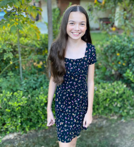Lauren Torres, now 12 years old, smiles as she stands in her family's garden.