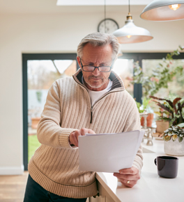 a caucasian man in his kitchen reading instructions for an at-home test for colon cancer