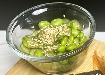 Quick and refreshing cucumber edamame salad is served in a clear bowl.