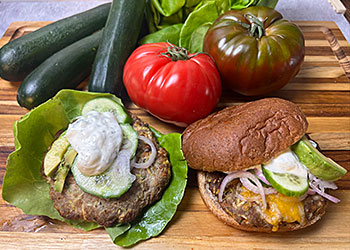 Turkey zucchini burger with zesty lemon yogurt sauce are displayed one with lettuce wrap and one with bun.