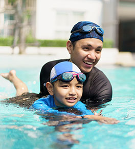 Asian father is teaching his son how to swim.