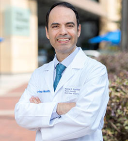 UCI Health hearing specialist Dr. Hamid Djalilian in white coat with arms folded.