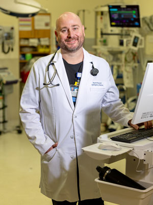dr ryan gibney wearing a white coat and standing in an emergency room