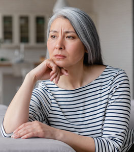 a graying woman wearing a striped top suffering from symptoms of genitourinary syndrome of menopause (GSM)