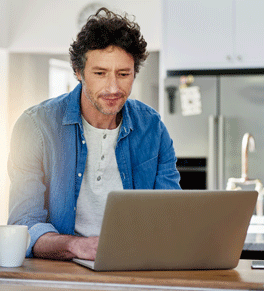a man wearing a blue shirt over a white t-shirt with mild cognitive impairment uses a laptop
