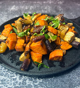 Sriracha honey roasted root vegetables are piled high on a black cast iron skillet.