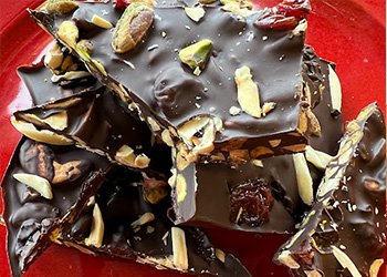 A rich and delicious pile of ancho chili-cinnamon chocolate bark is displayed on a festive red plate.