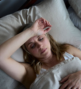 a woman with insomnia lays in bed frustrated that she can't fall asleep