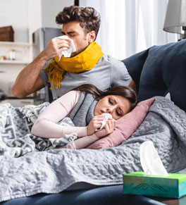 sick girlfriend and handsome boyfriend sneezing and holding napkins