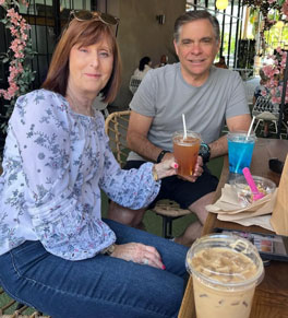 karen patterson and her husband greg sitting outside together at a table with cups of coffee at a cafe
