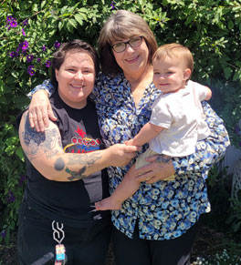 uci health cancer patient janet slinkard stands in front of bushes with her daughter and granddaughter
