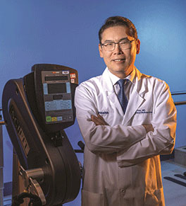 Dr. Jay Han, medical director of the UCI Health rehabilitation program, stands beside an exercise machine used to help patients recovering from traumatic injury to regain their strength and coordination.