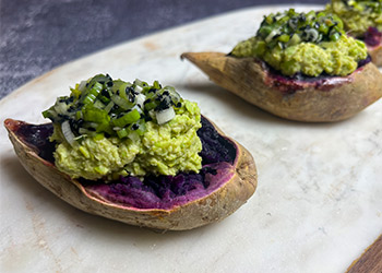 Deep purple Okinawan sweet potatoes with miso-edamame smash are displayed on a marble cutting board.