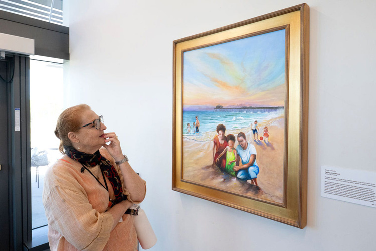 Ellen Khoudari, senior project manager in UCI Health Planning, Design & Construction, admires “Family at the Beach,” by Moises Camacho at uci health — irvine,, featuring a family playing in the sand