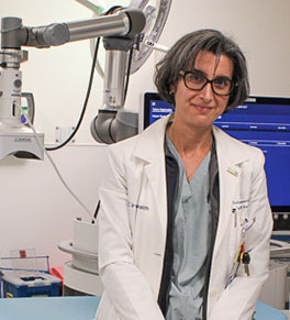 UCI Health interventional radiologist Dr. Nadine Abi-Jaoudeh stands in front of a machine n a radiology procedure suite.