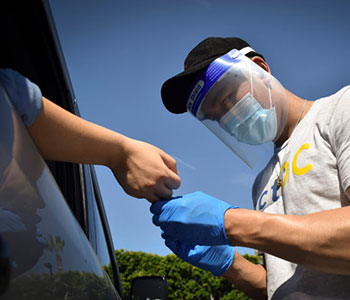 A medically trained UCI volunteer collects a blood sample from a study participant at a drive-through antibody testing station in Orange County.