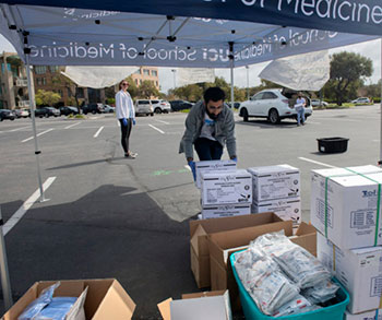 UCI medical student Mehron Dhillon stacks donations of personal protective equipment during a drive for supplies in the UCI School of Medicine parking lot.