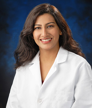 UCI Health infectious disease specialist Dr. Shruti K. Gohil photographed in white coat on a blue background.