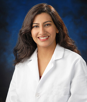 UCI Health infectious disease specialist Dr. Shruti K. Gohil photographed in white coat on a blue background. 