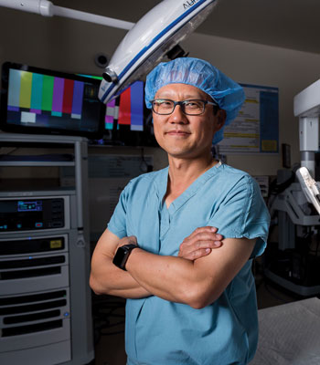 uci health physician dr. david lee talks to healthline about the trend of prostate cancer monitoring, standing in scrubs in operating room 