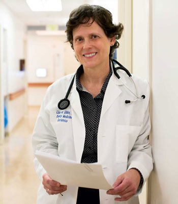 uci health geriatrician dr. lisa gibbs in a hallway holding clipboard wearing white coat, quoted in us news and world report