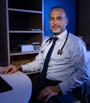 uci health sleep medicine specialist dr rami khayat wearing stethoscope, shirt and tie sitting at desk