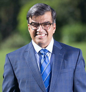 uci health neurologist Tahseen Mozaffar outdoors wearing blue suit and tie; he was the uci pi on a study of patients who were treated with Descartes-08, a cutting-edge RNA CAR-T (rCAR-T) therapy for the debilitating autoimmune neurological disease myasthenia gravis (MG). 