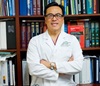 uci health Dr. Kenneth J. Chang, executive director of the UCI Health Digestive Health Institute (DHI) and an expert in endoscopic approaches to bariatric surgery standing in front of bookshelf wearing white lab coat with arms crossed and smiling