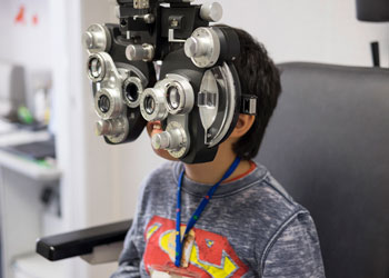 a child wearing a superman shirt gets an eye exam at uci health; dr donny suh speaks to us news and world report about the importance of regular eye exams