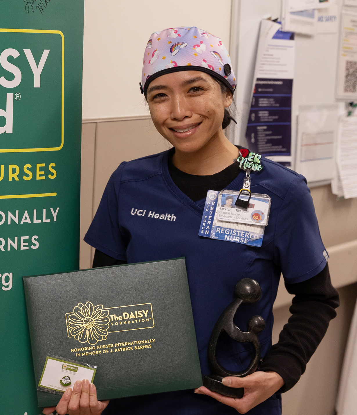 uci health nurse jackie santacruz wearing scrubs holding DAISY award and smiling