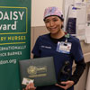 uci health nurse jackie santacruz wearing scrubs holding DAISY award and smiling