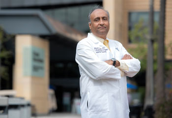 alpesh amin wearing white coat standing in front of uci health douglas hospital