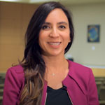 uci health als researcher and physician namita goyal standing in an office wearing black top and burgundy cardigan