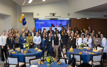 uci health nursing team at magnet recognition ceremony 2023; group of nurses standing behind tables with balloons in the background