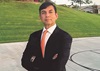 ranjan gupta wearing dark suit red tie and white shirt standing outside on sidewalk in front of lawn