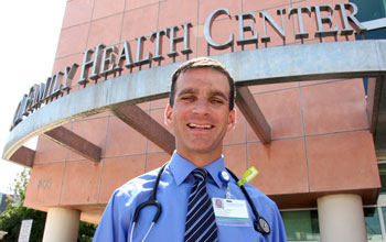 uci health family medicine physician dr charles vega wearing blue shirt, tie and stethoscope in front of the uci health family health center santa ana