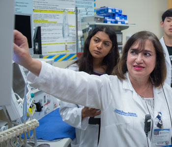 uci health pediatrician behnoosh afghani wearing a white coat and instructing medical students in a lab