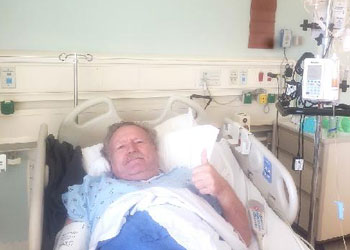 orange county chef pascal olhats laying in a hospital bed in a blue gown receiving stem cells from his daughter who lives in france
