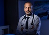 uci health sleep medicine specialist dr. rami khayat in his office wearing a stethoscope and sitting on an exam bed bathed in blue light; dr khayat explains the importance of REM sleep