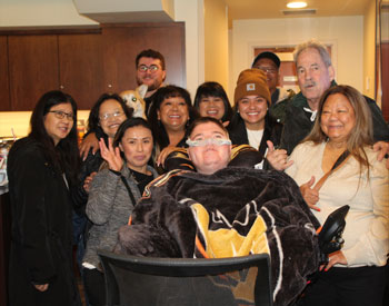 uci health patient jason fox  in a honda center suite watching an anaheim ducks game with his family surrounding him