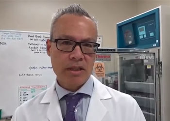uci health transfusion medicine expert dr. minh-ha tran wearing a white lab coat and tie standing in front of the uci health blood bank