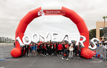 a crowd gathers under the starting line and balloons saying 100 years at the orange county heart and stroke walk