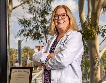 UCI Health Parkinson's disease expert Dr. Claire Henchcliffe stands in her office with arms crossed.