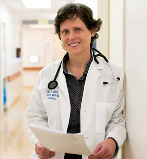 uci health geriatrician dr lisa gibbs wearing a white coat and stethoscope standing in the hallway of the UCI Health SeniorHealth Center at uci medical center in orange
