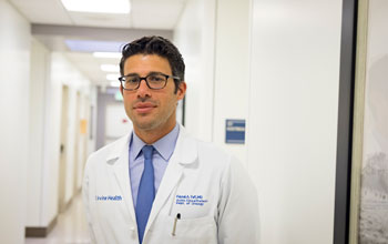 uci health mens health specialist and urologist dr faysal yafi in a lit hallway wearing a blue shirt and tie and white coat