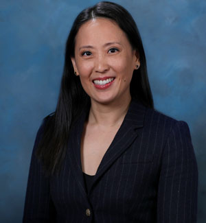 uci health chief procurement officer susanna rustad wearing a dark suit with a blue studio background